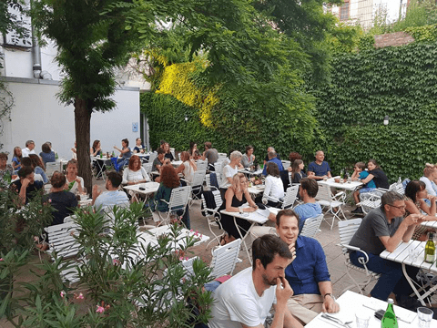 Der Sommergarten der Osteria N.1 mit weißen Stühlen und efeubewachsenen Wänden