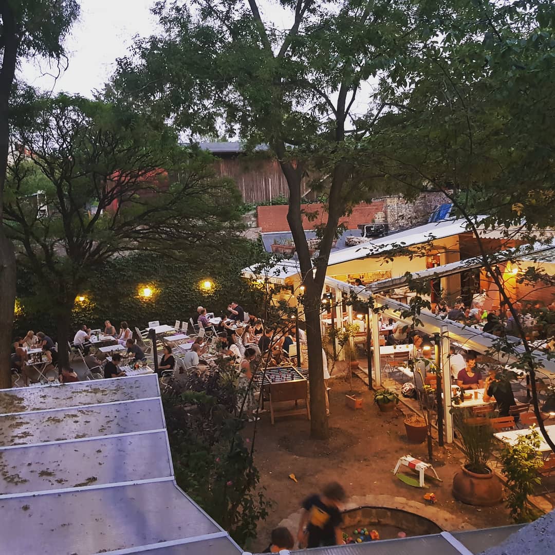 Der Innenhof der Osteria N.1 von oben in der Abenddämmerung, mit Tischen unter Bäumen