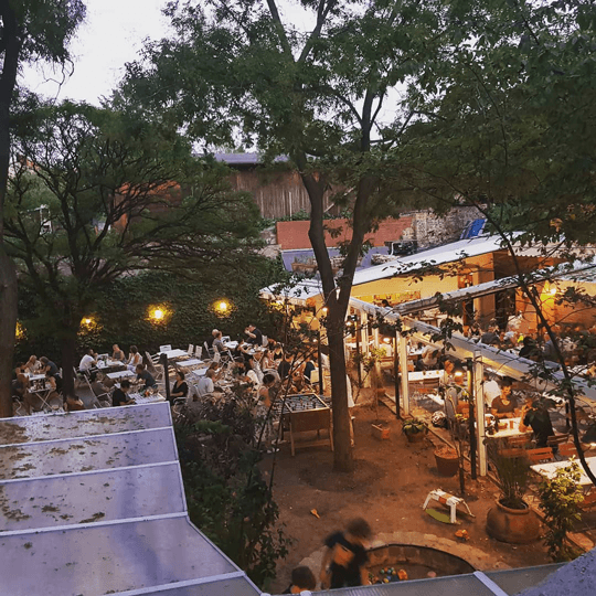 Der Innenhof der Osteria N.1 von oben in der Abenddämmerung, mit Tischen unter Bäumen